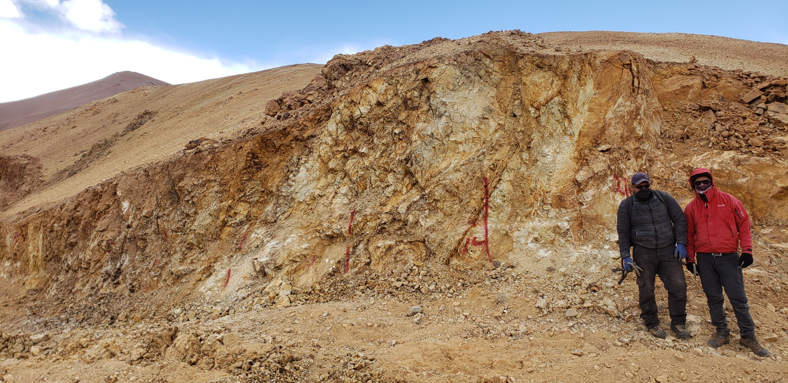 Geologists examining the Cura prospect trench with argillic alteration.